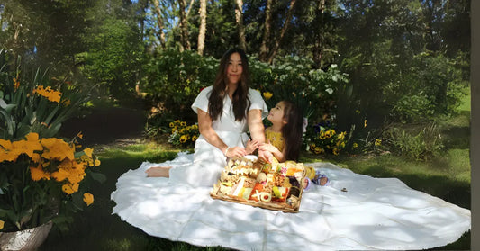 how to style a cheese board with fresh flowers, mixed cheeses, meats, and fruit on a white picnic blanket