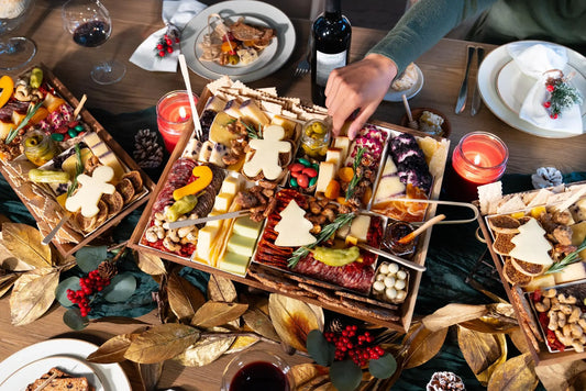 Christmas party charcuterie board with festive tree and gingerbread-shaped cheeses, meats, nuts, and holiday garnishes on a decorated table