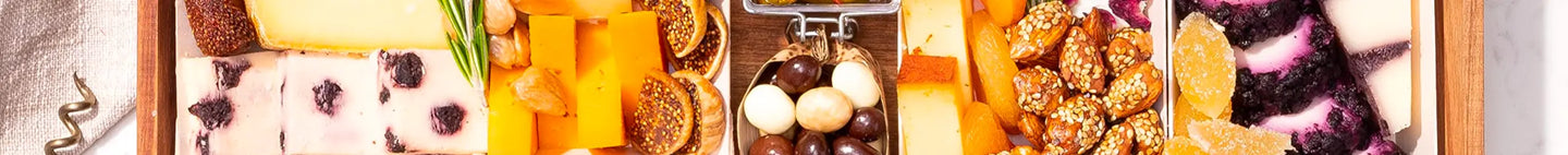 Close-up view of a charcuterie board section featuring cheeses, nuts, figs, and colorful dried fruits.