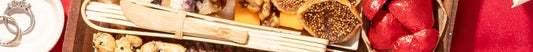 Holiday charcuterie board with dried figs, candied nuts, crackers, and foil-wrapped chocolates on a red.
