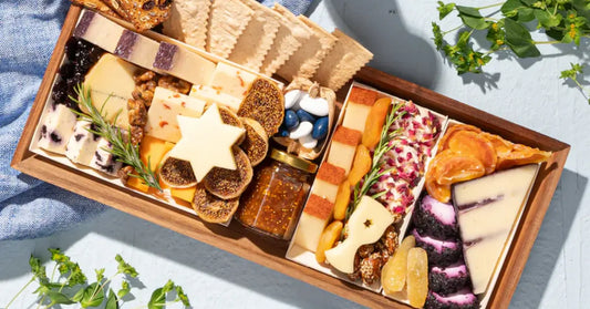 Charcuterie board with cheese, figs, dried fruits, and crackers, garnished with a rosemary sprig for a fresh look