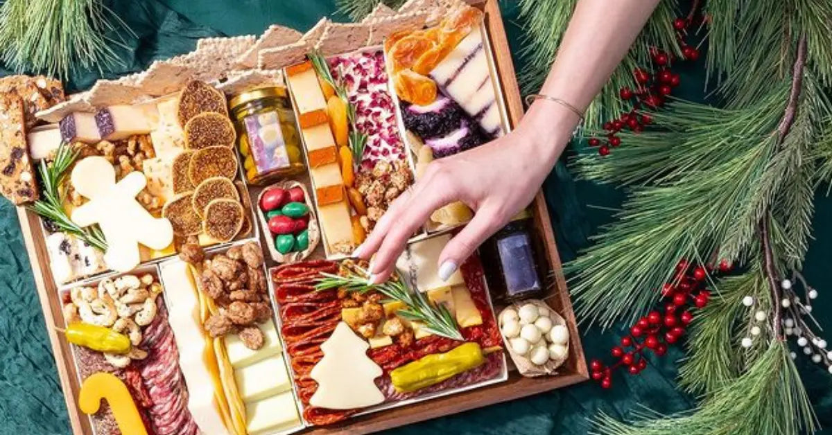 Holiday charcuterie board with festive cheeses, nuts, and meats, decorated with pine branches and red berries