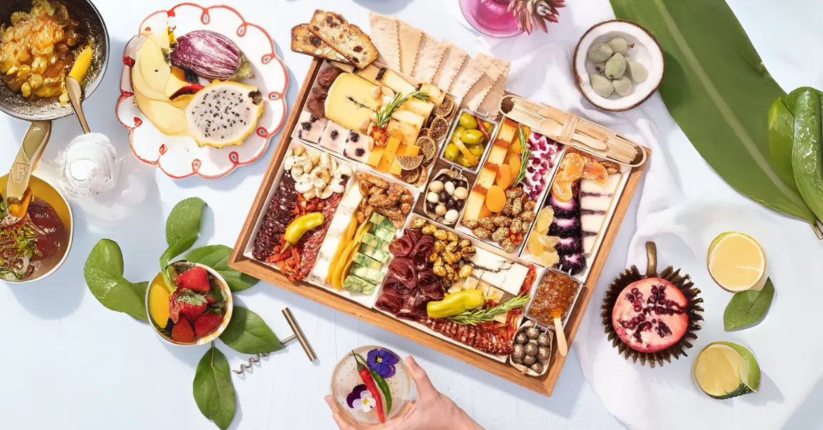 Mexican charcuterie board featuring artisanal cheeses, cured meats, dried fruits, nuts, crackers, and vibrant tropical flavors in a festive spread.