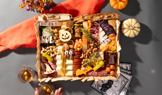 Boarderie's CharBOOterie — a Halloween Cheese and Charcuterie board with a jack-o-lantern cheese, googly-eyed cheese characters, artisan meats, candy corn, fig jam, and a gourmet assortment of artisan cheeses in a reusable acacia wood board
