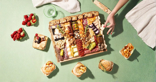 baked brie charcuterie board flat lay with a full grazing box of cheeses, meats, crackers, berries, and mini brie pastries