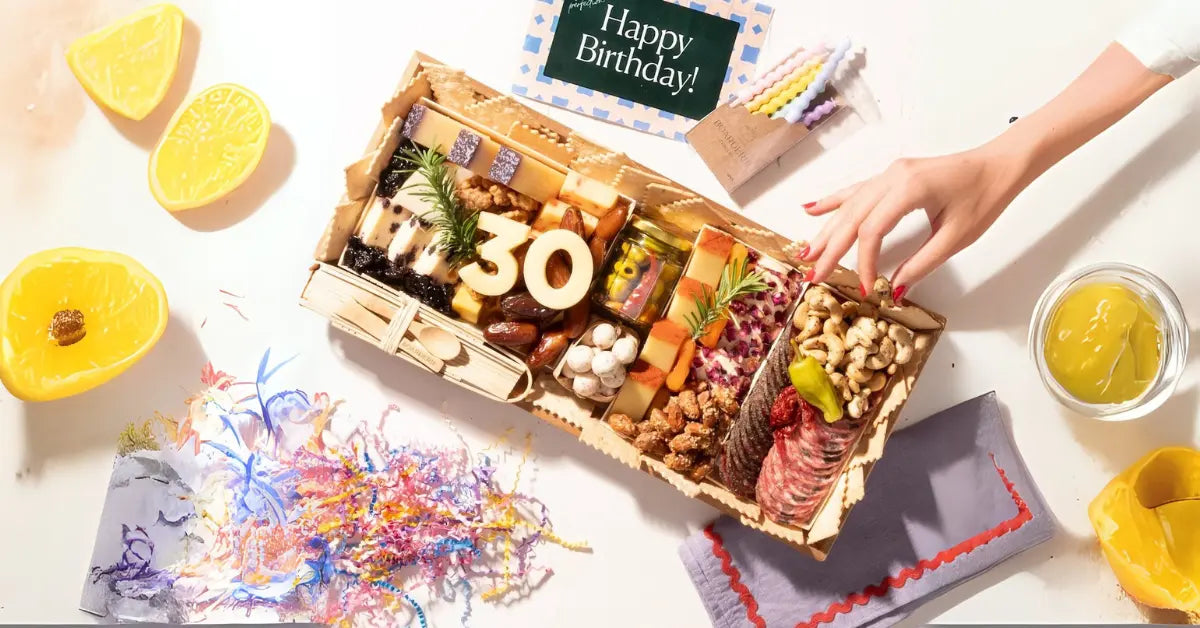 Birthday charcuterie board with “30” cheese numbers, meats, cheeses, nuts, and festive decorations.
