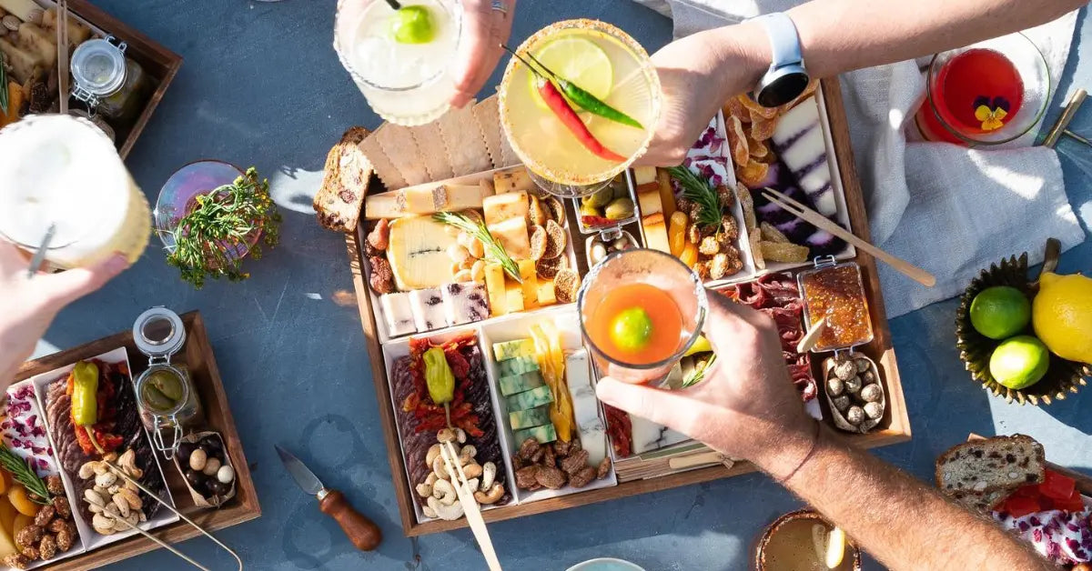 Meat cheese board surrounded by cocktails and fresh citrus, perfect for a summer gathering.