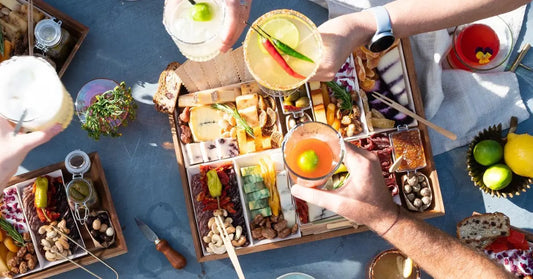 Meat cheese board surrounded by cocktails and fresh citrus, perfect for a summer gathering.