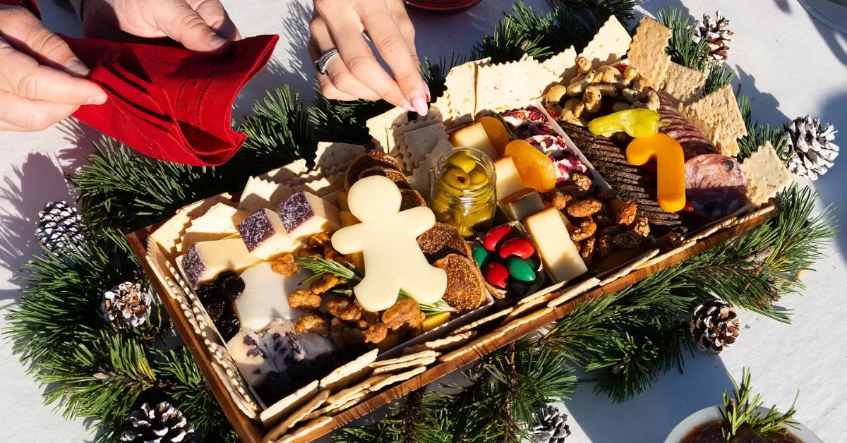 Charcuterie board styling with festive holiday decor, featuring cheeses, meats, nuts, crackers, and Christmas-themed garnishes