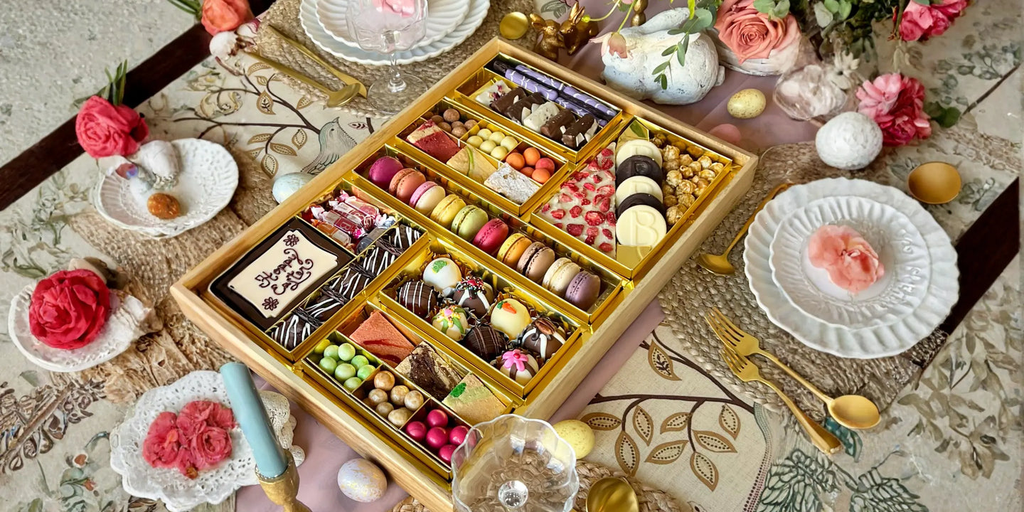 charcuterie tray filled with macarons, truffles, chocolates, and candies displayed on a floral Easter table setting