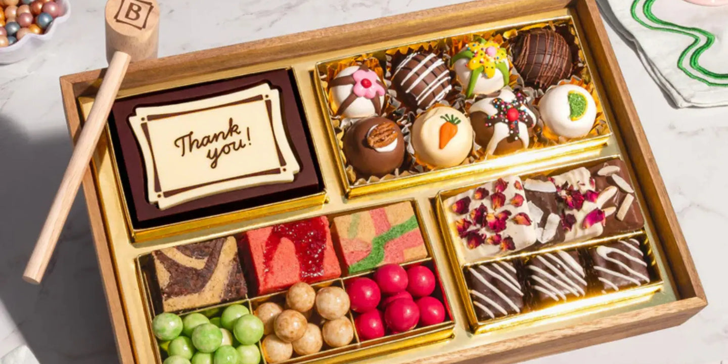cheese and meat board packed with chocolates, truffles, and brownies in a gold-lined wooden tray with a thank you message