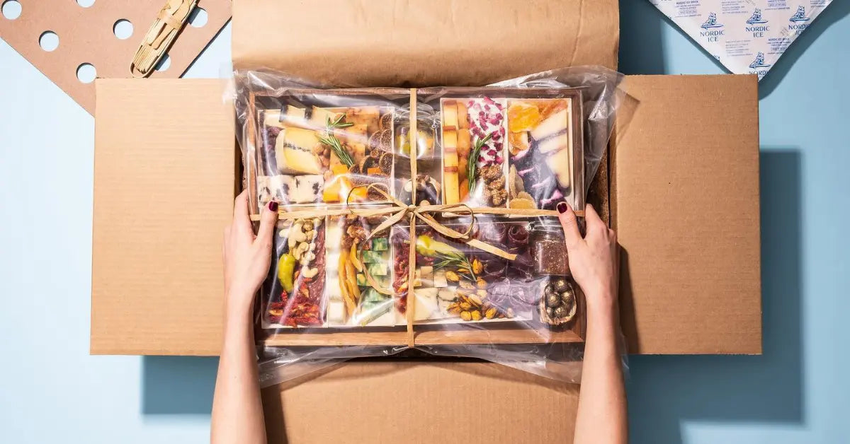 Classic charcuterie board sealed in plastic and tied with twine inside a shipping box, ready for delivery or gifting.