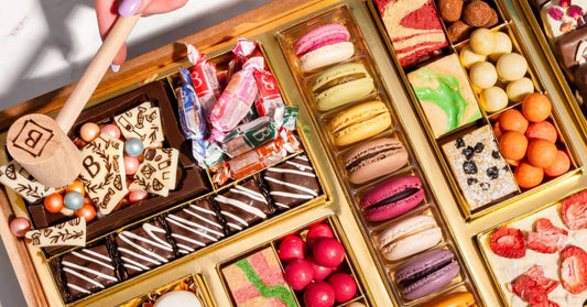 dessert charcuterie board ideas showcasing macarons, cake bites, candies, and chocolate-covered confections