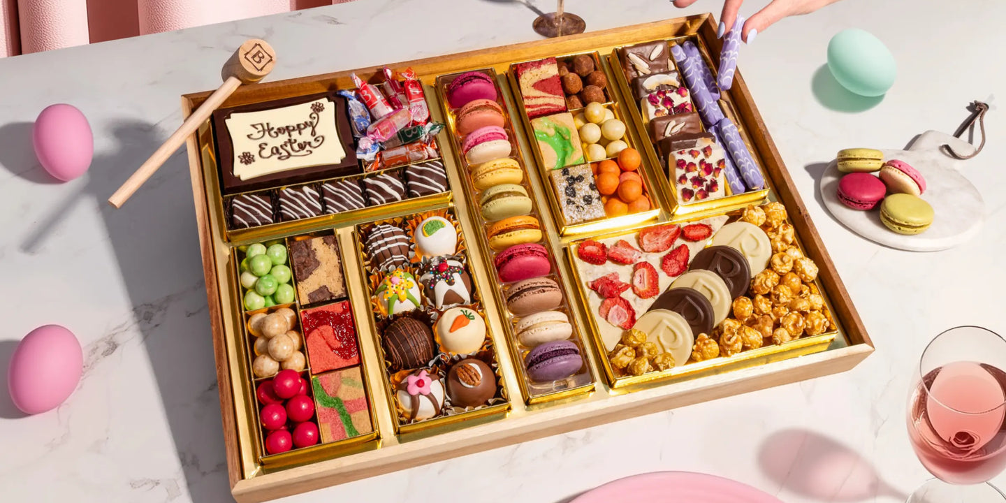 dessert grazing table ideas with a large Easter board of macarons, truffles, strawberry bark, and candies styled with pastel eggs