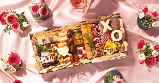 Easy romantic charcuterie board – Pre-arranged, ready-to-serve charcuterie box with assorted bites and Valentine details (heart shapes, ribbon) for a simple romantic setup.
