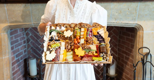 Fall charcuterie board with autumn leaf-shaped cheeses, meats, nuts, dried fruits, and crackers arranged in a festive tray