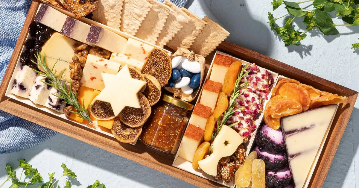 Festive cheese and meat board arranged with dried fruits, crackers, rosemary, and colorful cheeses in a wooden box
