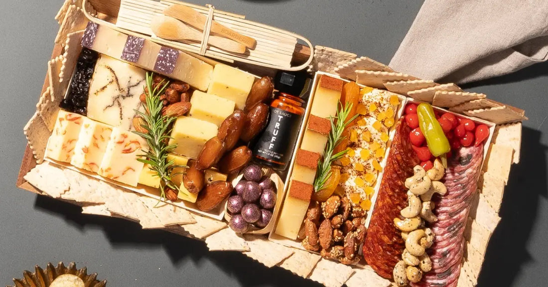 Gourmet charcuterie board featuring assorted cheeses, nuts, meats, dried fruits, crackers, and a bottle of truffle hot sauce