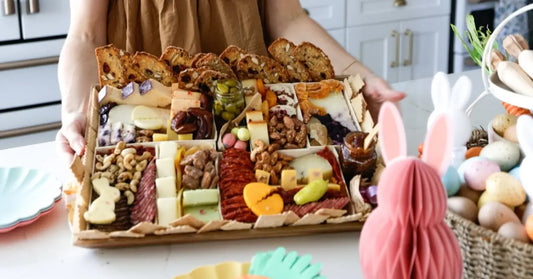 Cheese board setup with Easter-themed accents and colorful snacks beside bunny decorations and pastel eggs.
