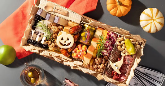 Halloween charcuterie board featuring festive cheeses, meats, candy corn, and spooky decorations in a wooden tray