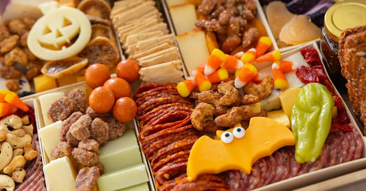 Halloween meat and cheese board with candy corn, cured meats, spooky cheese shapes, crackers, nuts, and festive garnishes