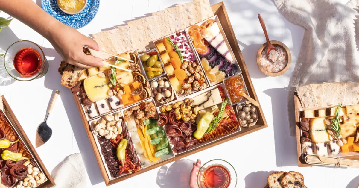 Large charcuterie board filled with assorted cheeses, meats, nuts, fruits, and crackers for entertaining.