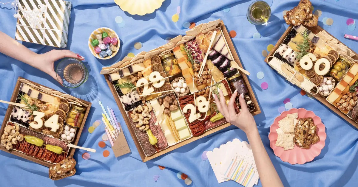 Meat and cheese tray with gourmet cheeses, cured meats, nuts, and crackers, decorated with number-shaped cheese for a festive celebration.