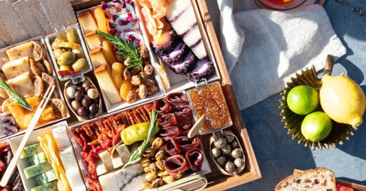 personalized charcuterie boards arranged in gift box with custom cheese letters, meats, nuts, crackers, and floral accents