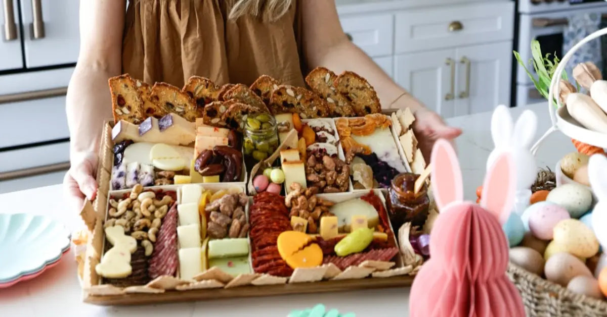 Premade meat and cheese tray with crackers, nuts, cured meats, and Easter-themed cheese cutouts on a kitchen counter.