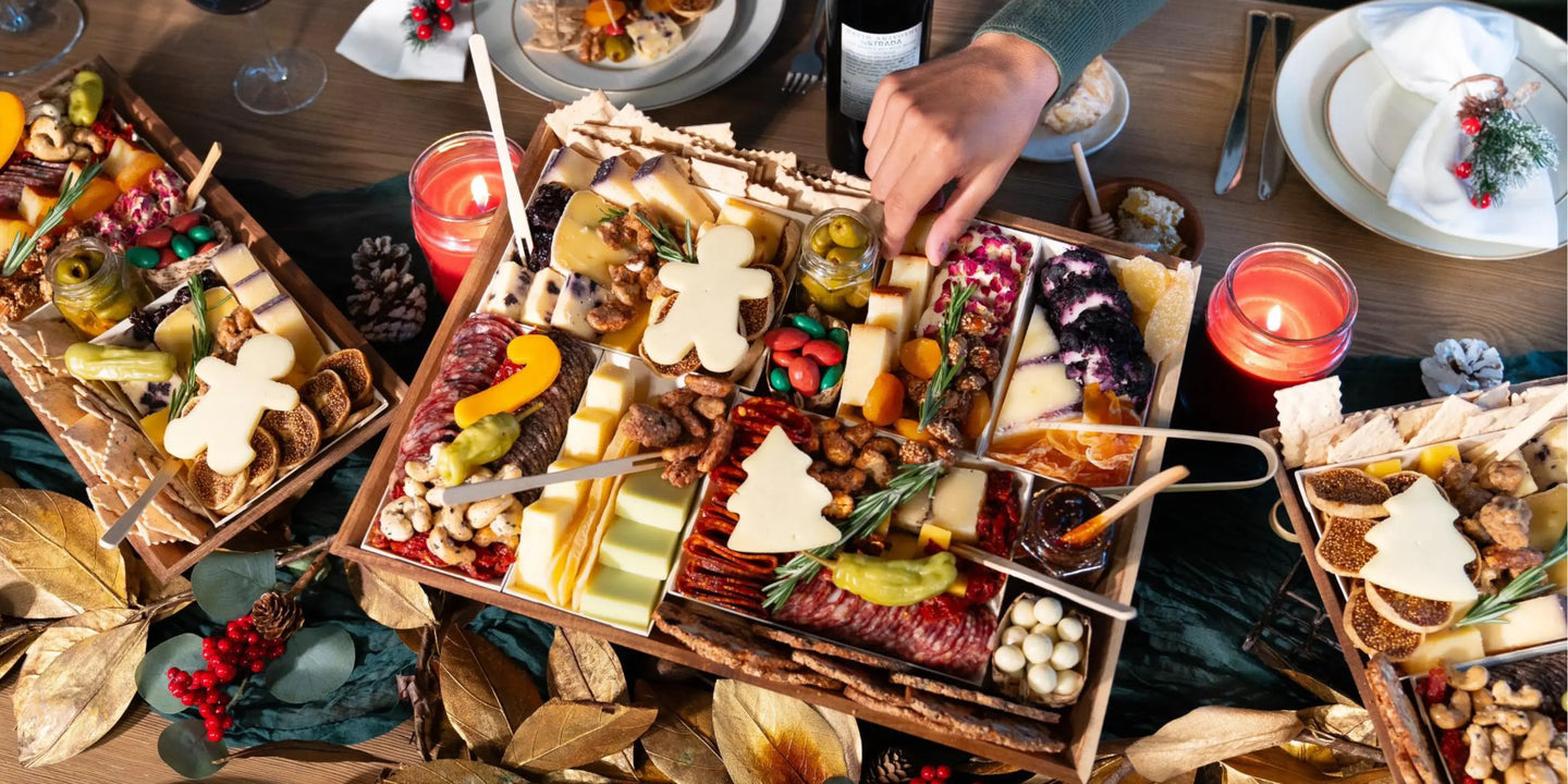 salty cured meats with cheddar and tree-shaped cheese on holiday boards with candles, pine cones, and red berries on a Christmas table