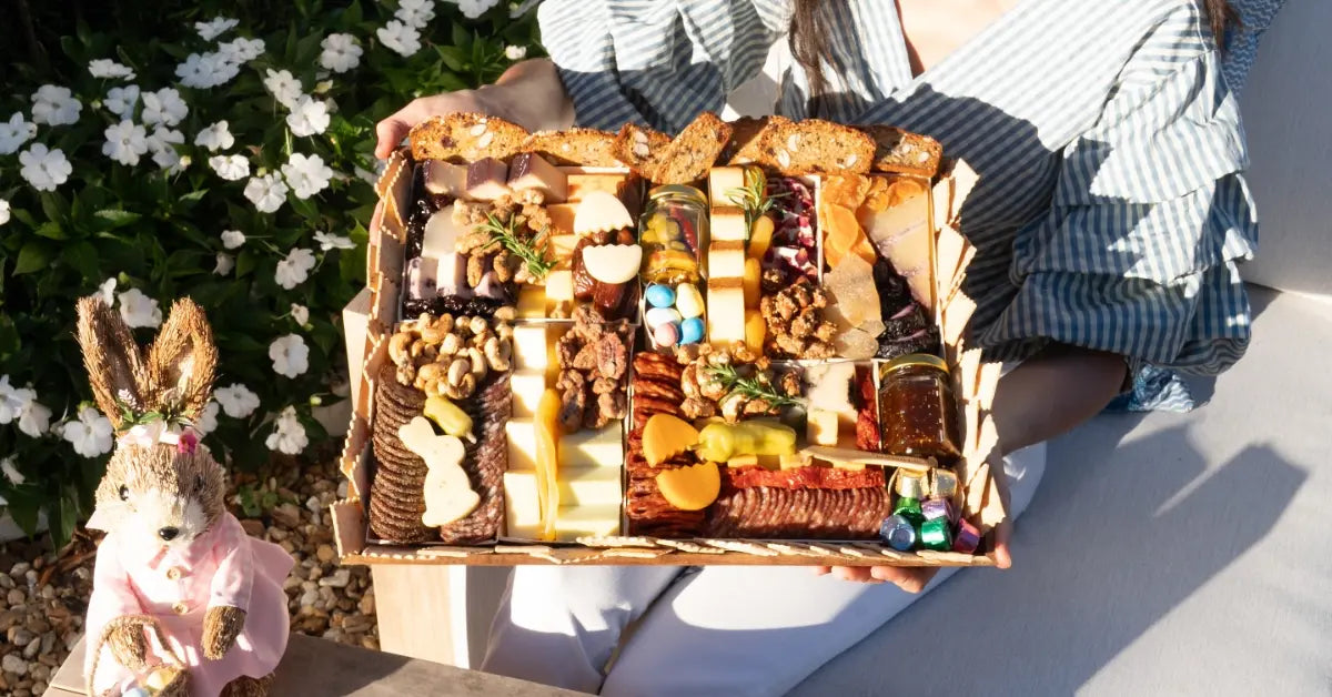 Snack charcuterie board filled with assorted cheeses, crackers, meats, and candies arranged festively for a spring picnic.