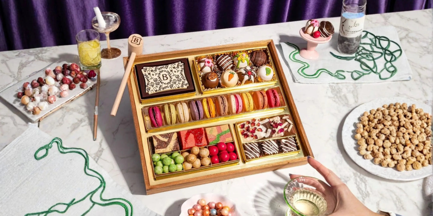 sweet grazing board ideas styled party spread with a dessert tray, small bowls of candy, drinks, and dessert accents on a marble surface