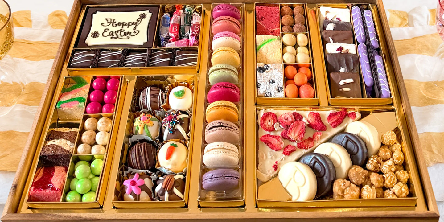 trendy dessert ideas in a large Easter board with macarons, truffles, chocolate bark, and colorful candies in a gold-lined wooden tray