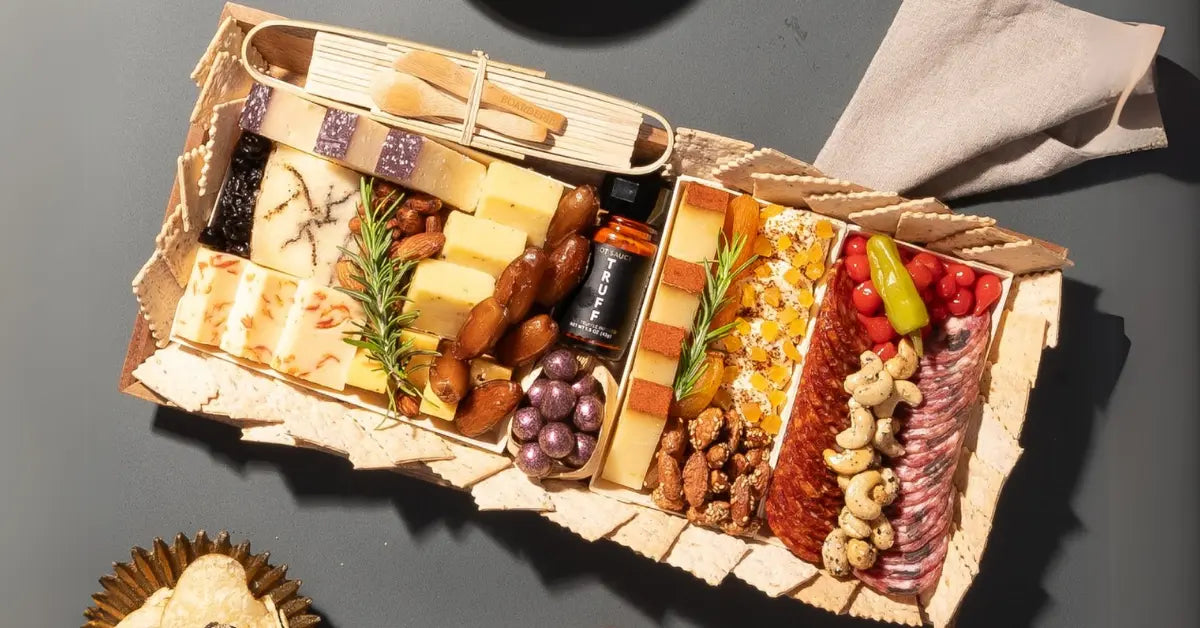 Truffle charcuterie board featuring gourmet cheeses, cured meats, nuts, crackers, dried fruits, and a bottle of truffle hot sauce