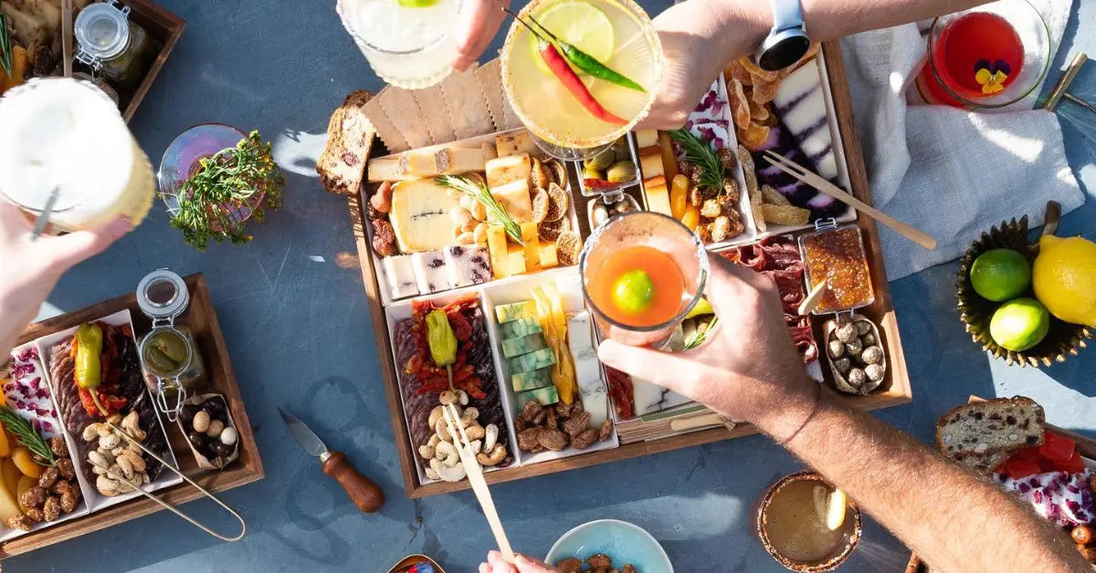 Wedding charcuterie board elegantly arranged with gourmet cheeses, meats, nuts, and fruits, surrounded by celebratory cocktails and appetizers