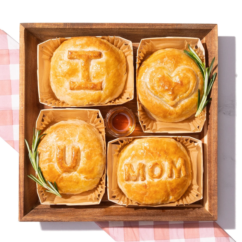 Mother's Day cheese board featuring baked brie with “I ♥️ U MOM” engravings, garnished with rosemary and honey.