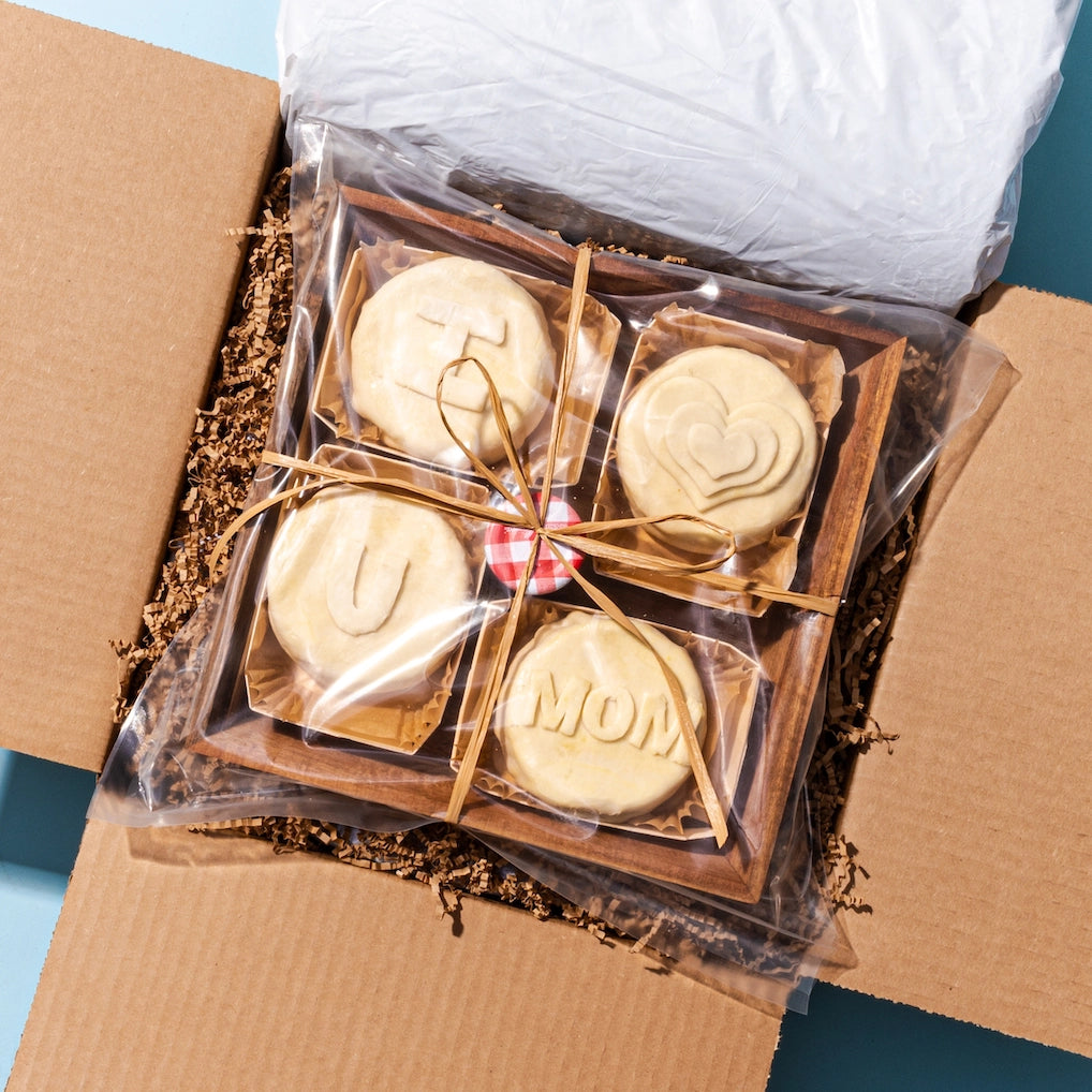 Gift box with a baked brie board featuring “I ♥️ U MOM” engravings, carefully packed with protective filling.