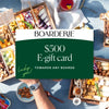 Assorted charcuterie boards with cheeses, meats, and nuts, promoting a $500 gift card for any board selection.