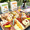 Birthday charcuterie board with "60" in cheese, colorful candles, meats, cheeses, and crackers on an outdoor table.