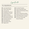 A beige ingredients list titled 'Ingredients' with a subtitle 'Accompaniments' and 31 listed food items in two columns, including dried cherries, dates, ginger, cashews, walnuts, almonds, mango slices, pepperconcini, sun dried tomatoes, figs, green olives, candy corn, gummy bears, and crackers.
