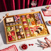 Gourmet dessert gift board featuring over 47 artisan chocolates, brownies, macarons, cakes, truffles, caramels & more on a reusable acacia wood board.