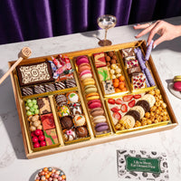 Gourmet dessert gift board featuring over 47 artisan chocolates, brownies, macarons, cakes, truffles, caramels & more on a reusable acacia wood board. Smash the chocolate box for a surprise.