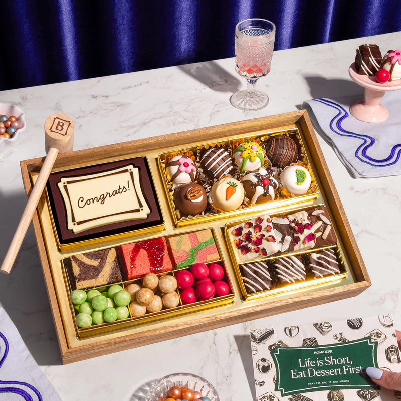 Assorted dessert box with a 'Congrats!' card on a marble table.