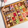Gourmet dessert gift board featuring over 47 artisan chocolates, brownies, macarons, cakes, truffles, caramels & more on a reusable acacia wood board. Smash the chocolate box for a surprise.