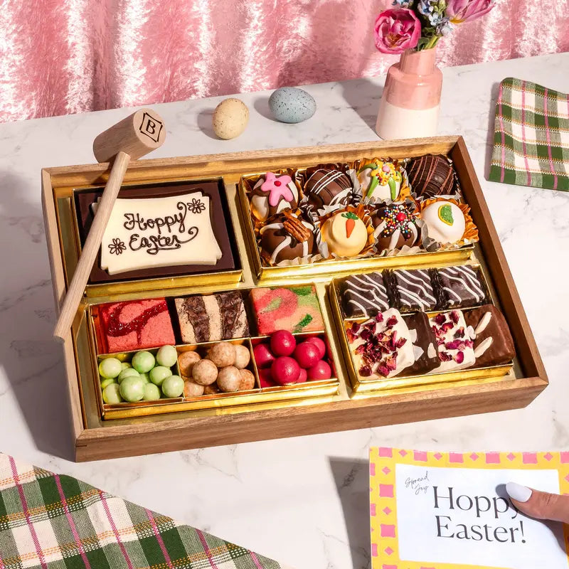 A small Easter themed charcuterie board of chocolates, truffles, candies, and a 'Happy Easter' cookie, paired with a handwritten Easter card.