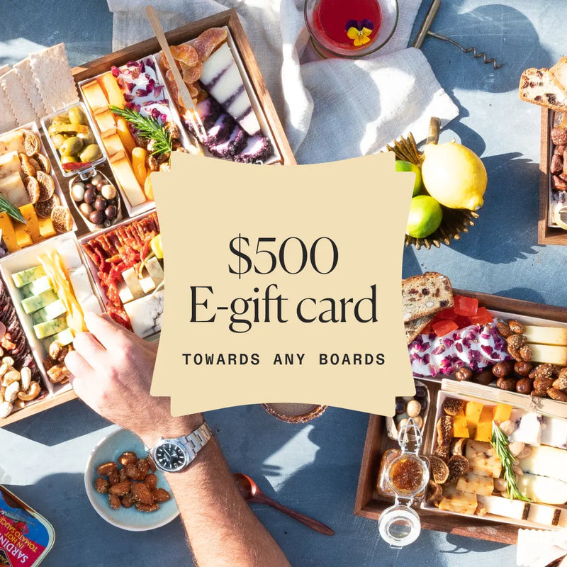 Assorted charcuterie boards with cheeses, meats, and nuts, promoting a $500 e-gift card for any board selection.