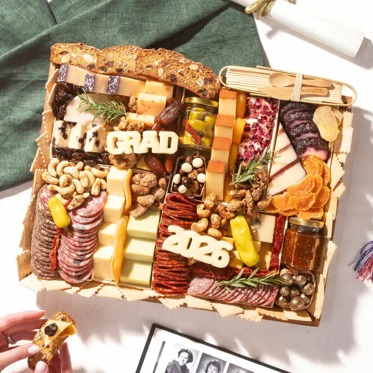 Graduation charcuterie board with cheeses, meats, nuts, and cheese letters spelling GRAD 2026.