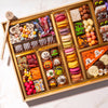 Close-up angled view of a large Halloween dessert board with Happy Halloween chocolate bark, wrapped hard candies, mummy brownie bites, an assorted macaron column, and hand-decorated skull, pumpkin, and eyeball truffles.