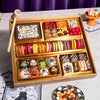 Medium Halloween dessert board in a gold-lined wooden tray with a row of colorful French macarons, chocolate truffles, brownie bites, candy, and a "Happy Halloween" chocolate plaque.