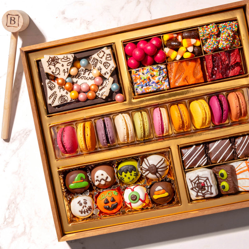 Overhead view of the Boarderie Halloween Medium Dessert Board with 30-plus gourmet treats, artisan French macarons, hand-decorated monster truffles, candy corn, brownies, and a chocolate smash box with a wooden mallet.